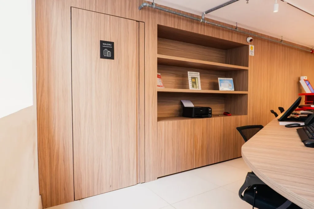 Recepção com painel, porta embutida e estante em madeira, projeto da Navarro Móveis Planejados no Moov Hotel São Paulo