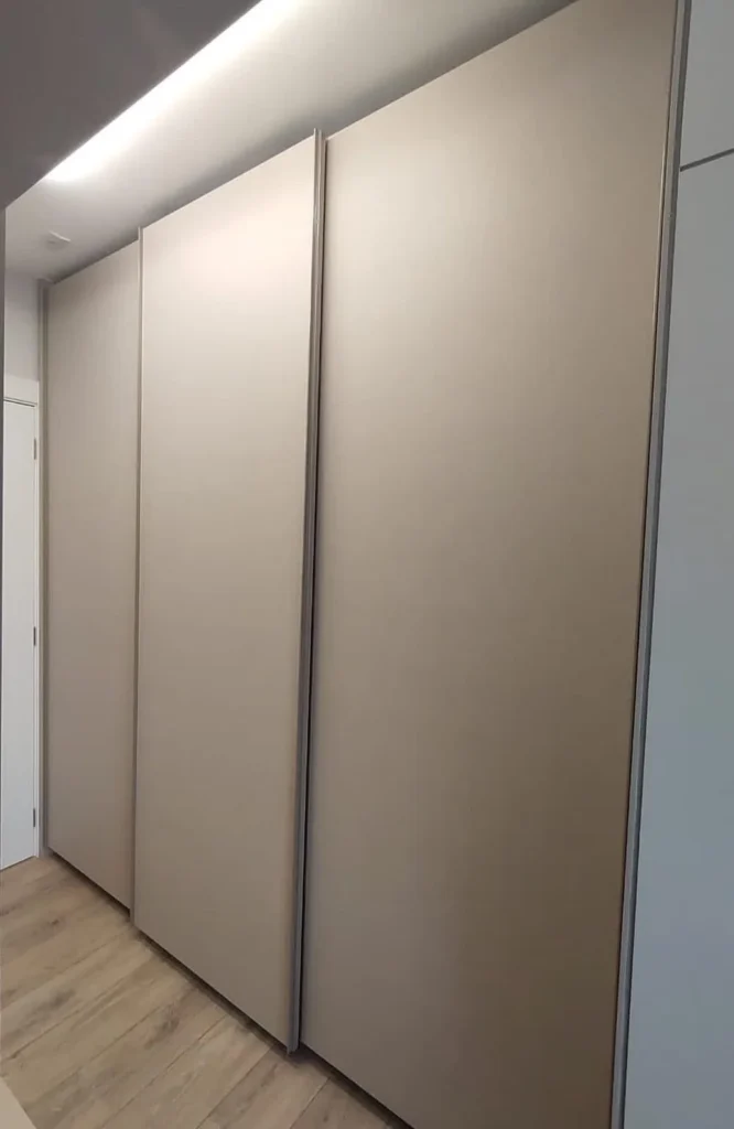 Guarda-roupa planejado com portas de correr em tom bege e iluminação no teto, projeto da Navarro Móveis Planejados