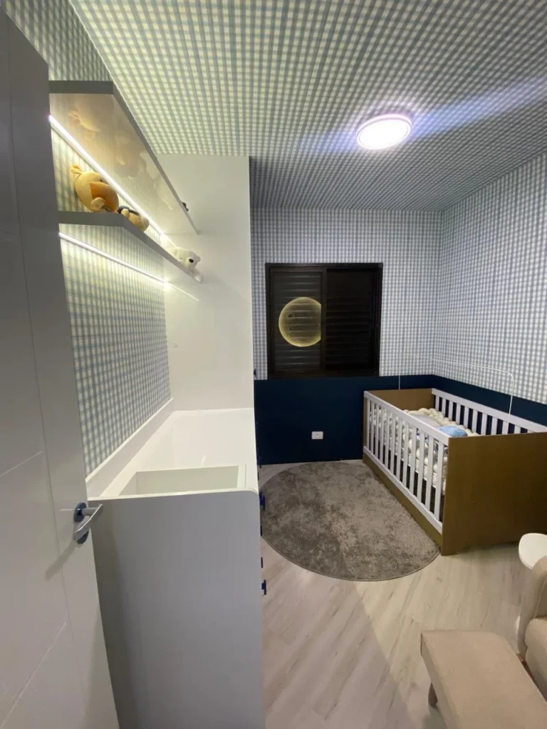 Quarto de bebê com móveis planejados brancos e prateleiras iluminadas — projeto da Navarro Móveis Planejados