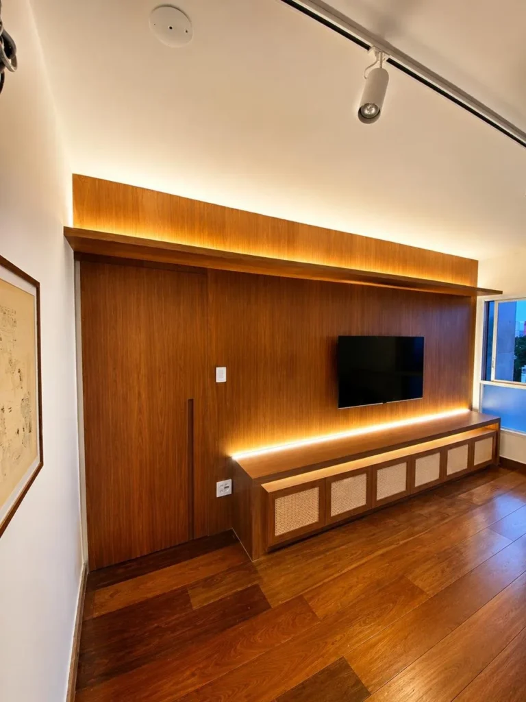 Painel de TV em madeira escura com iluminação embutida e rack com palhinha — projeto da Navarro Móveis Planejados