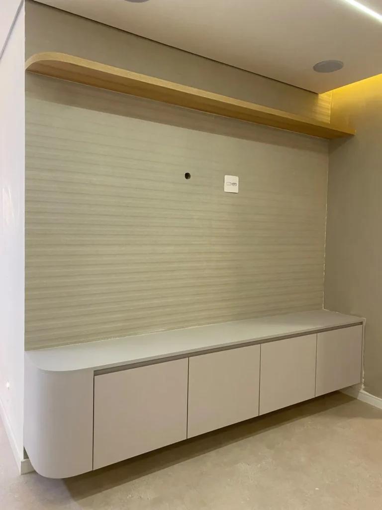 Sala com rack suspenso de cantos arredondados e prateleira em madeira, projeto da Navarro Móveis Planejados